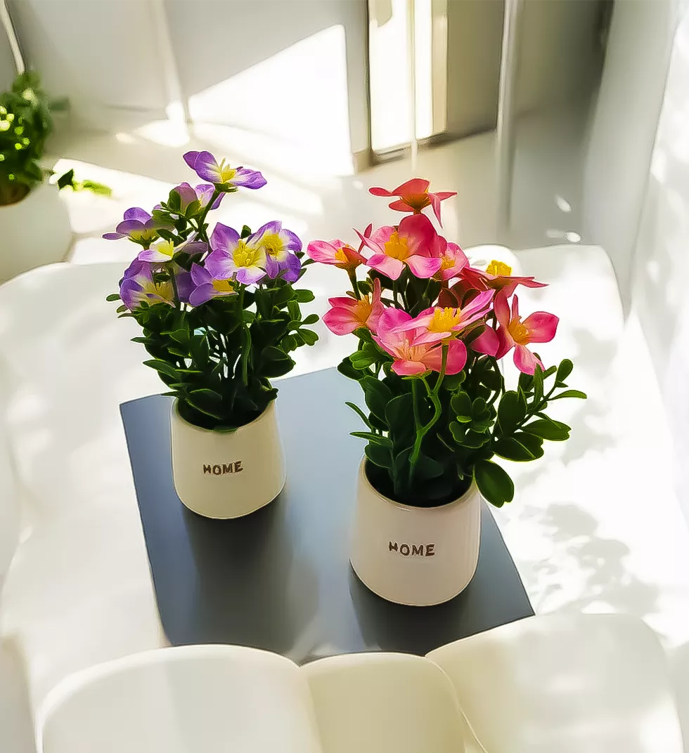 Two small potted artificial flower arrangements on a table.