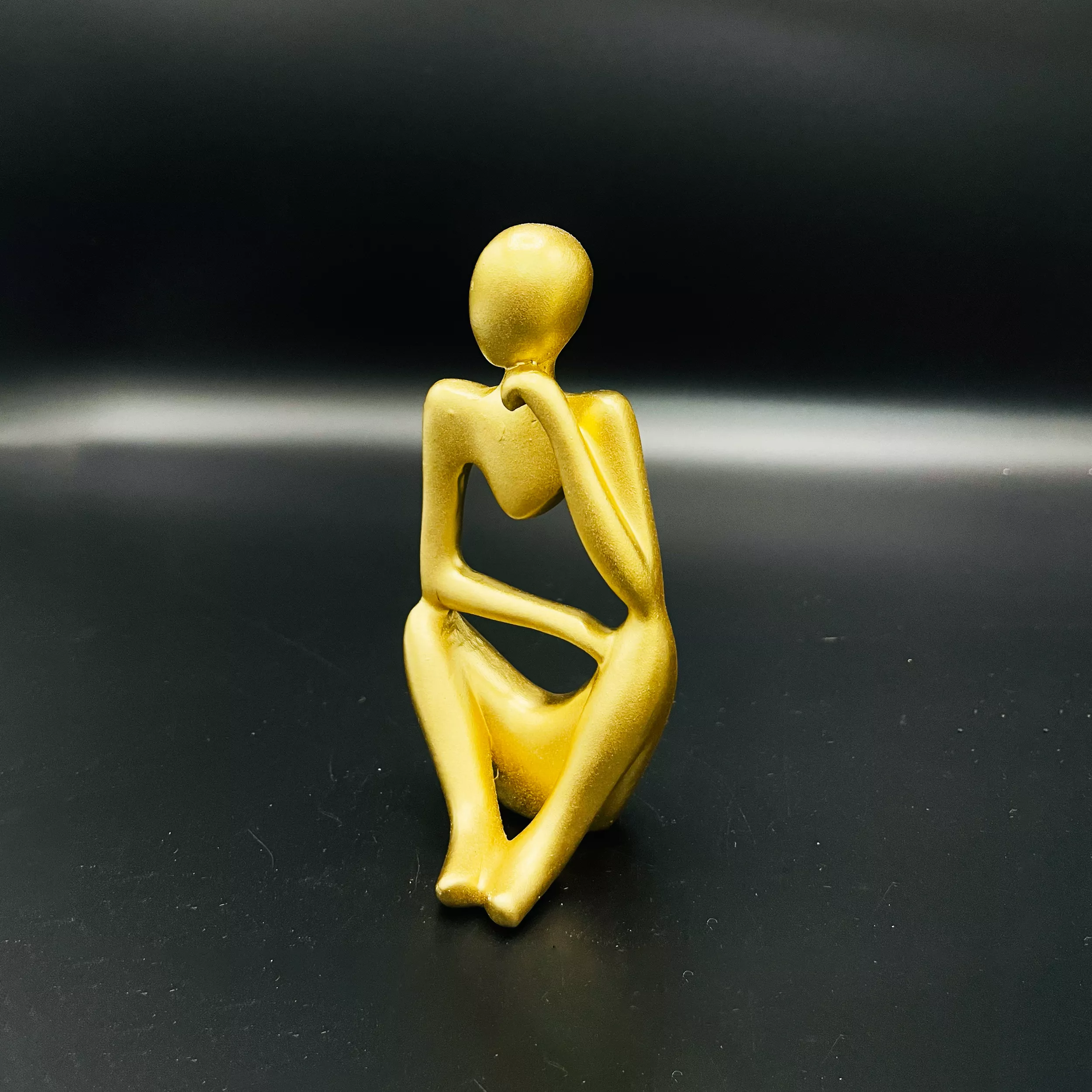 Gold Modern Abstract wisdom Statue on a dark surface.