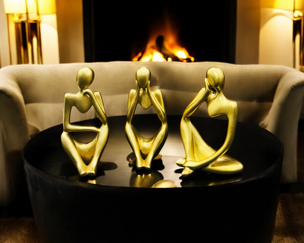 set of three golden hollow thinker sculptures on a table