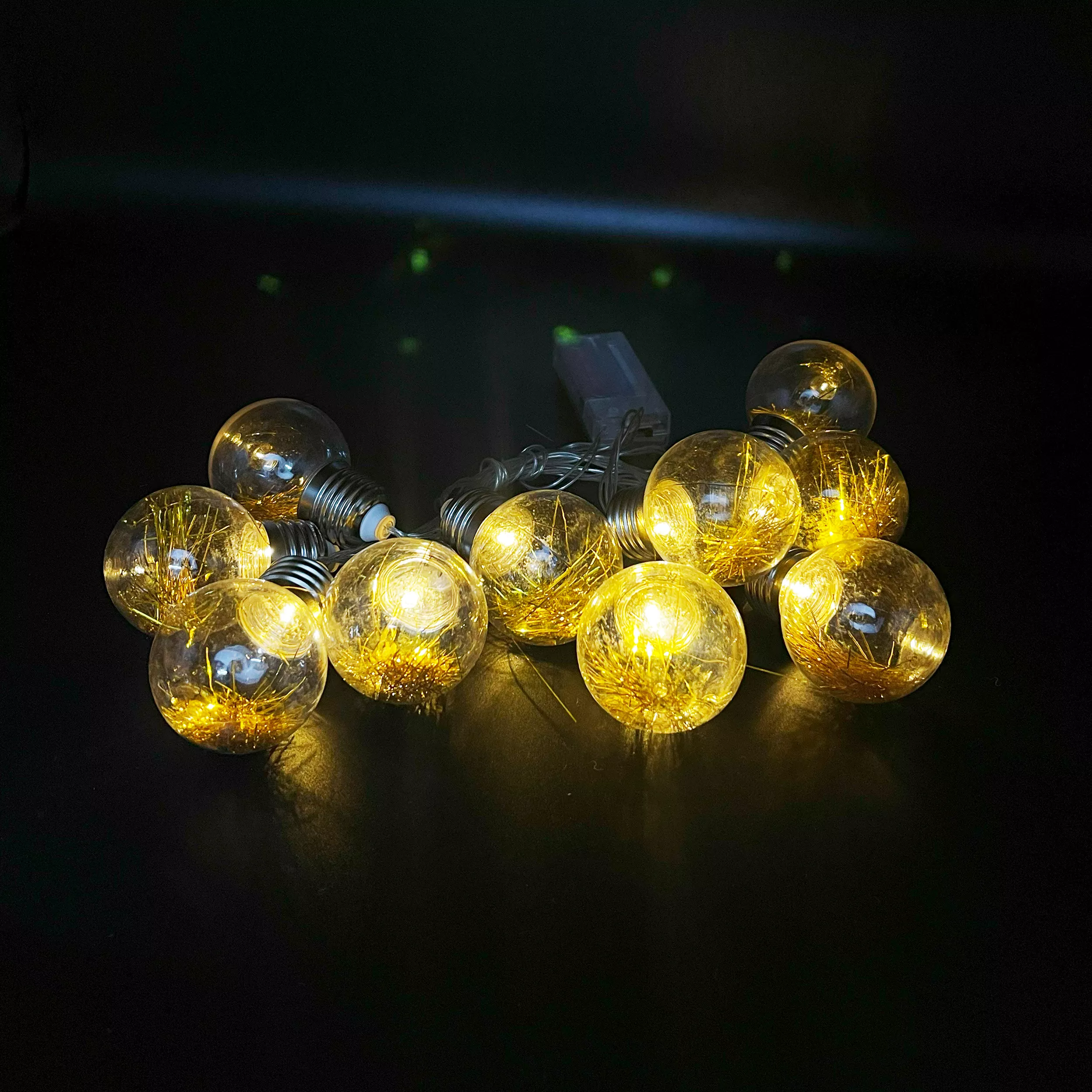 10 LED lighted lanterns with spherical bulbs on a dark surface.