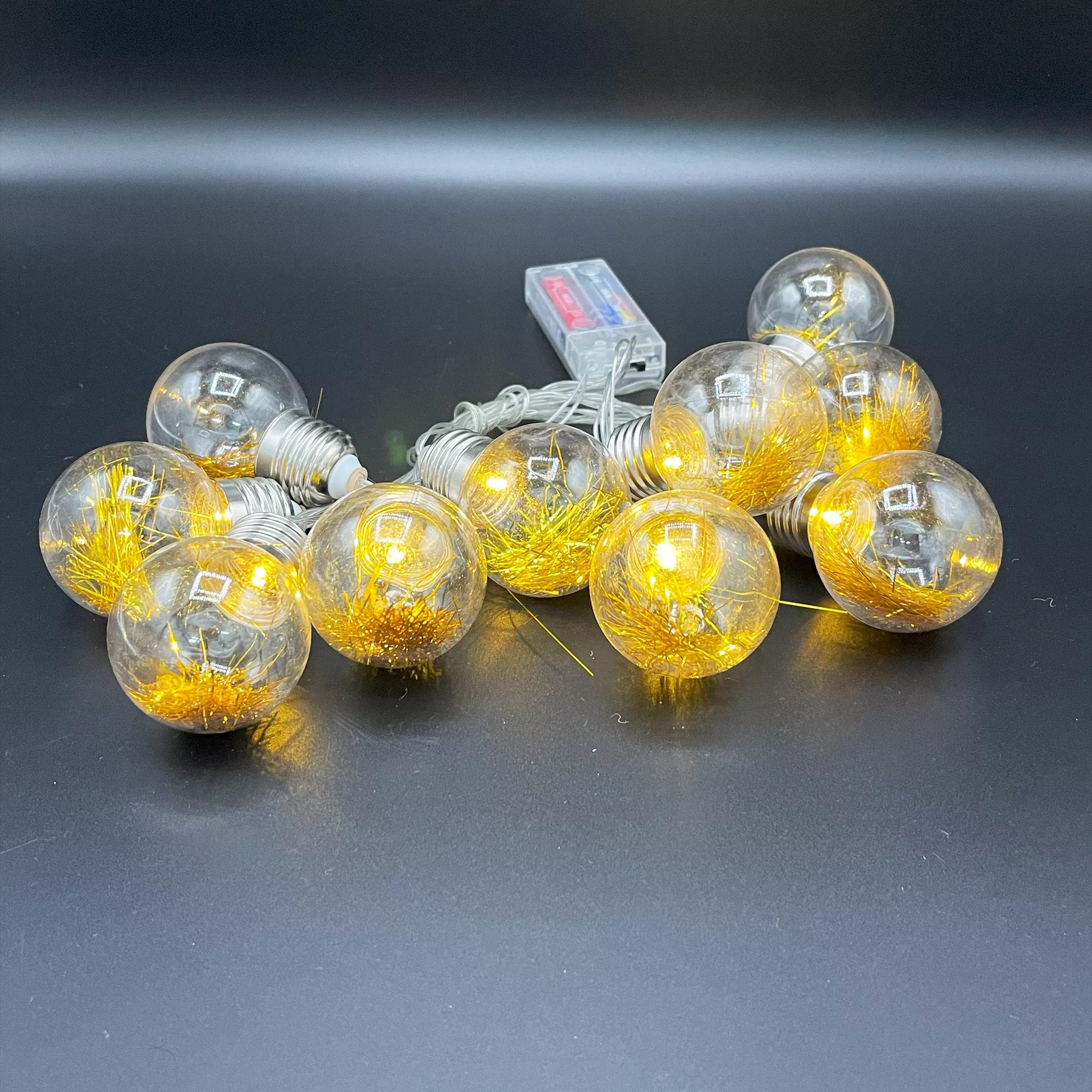 10 LED fairy lights with spherical bulbs on a dark surface.
