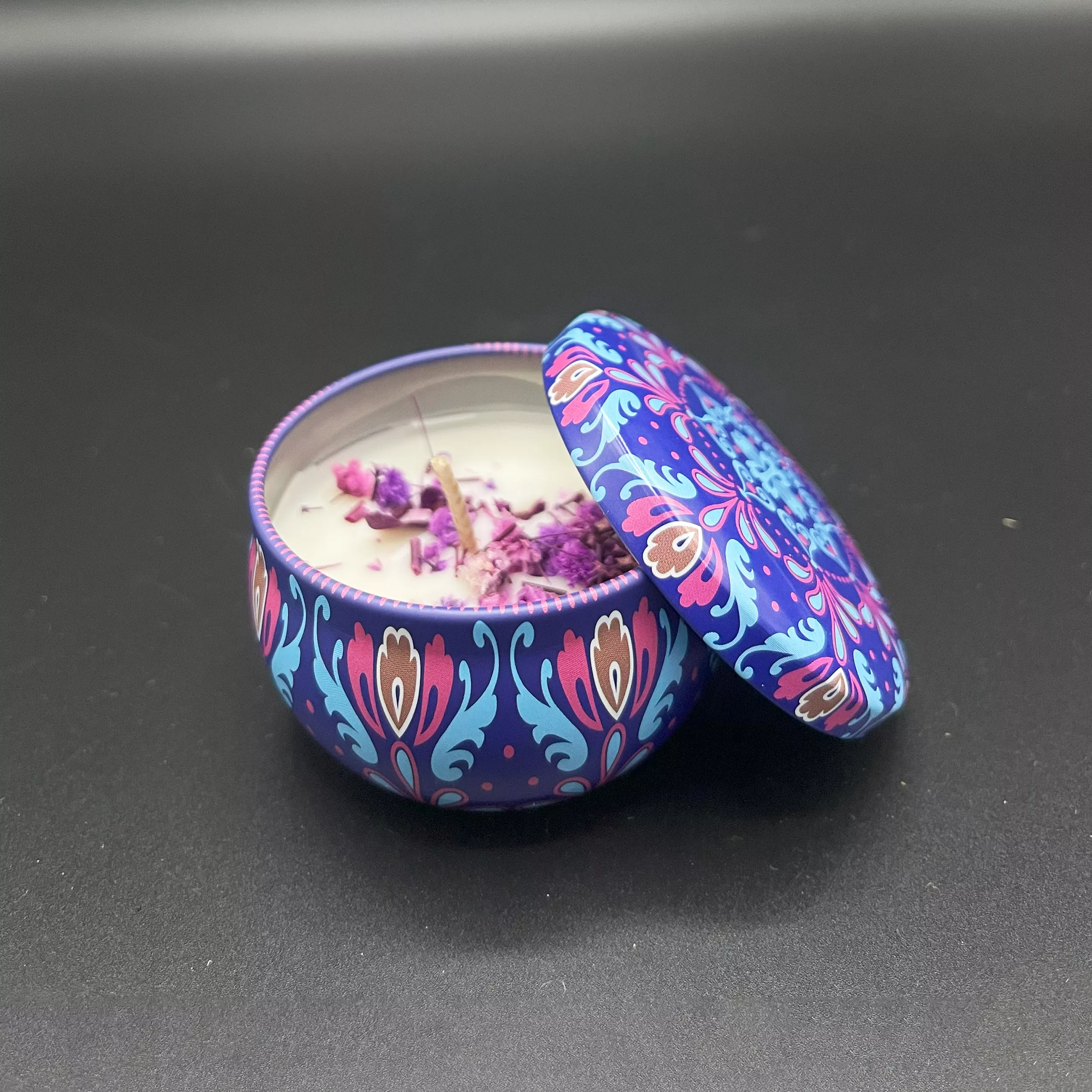 Blue and purple patterned scented candle tin jar with dried flowers inside.