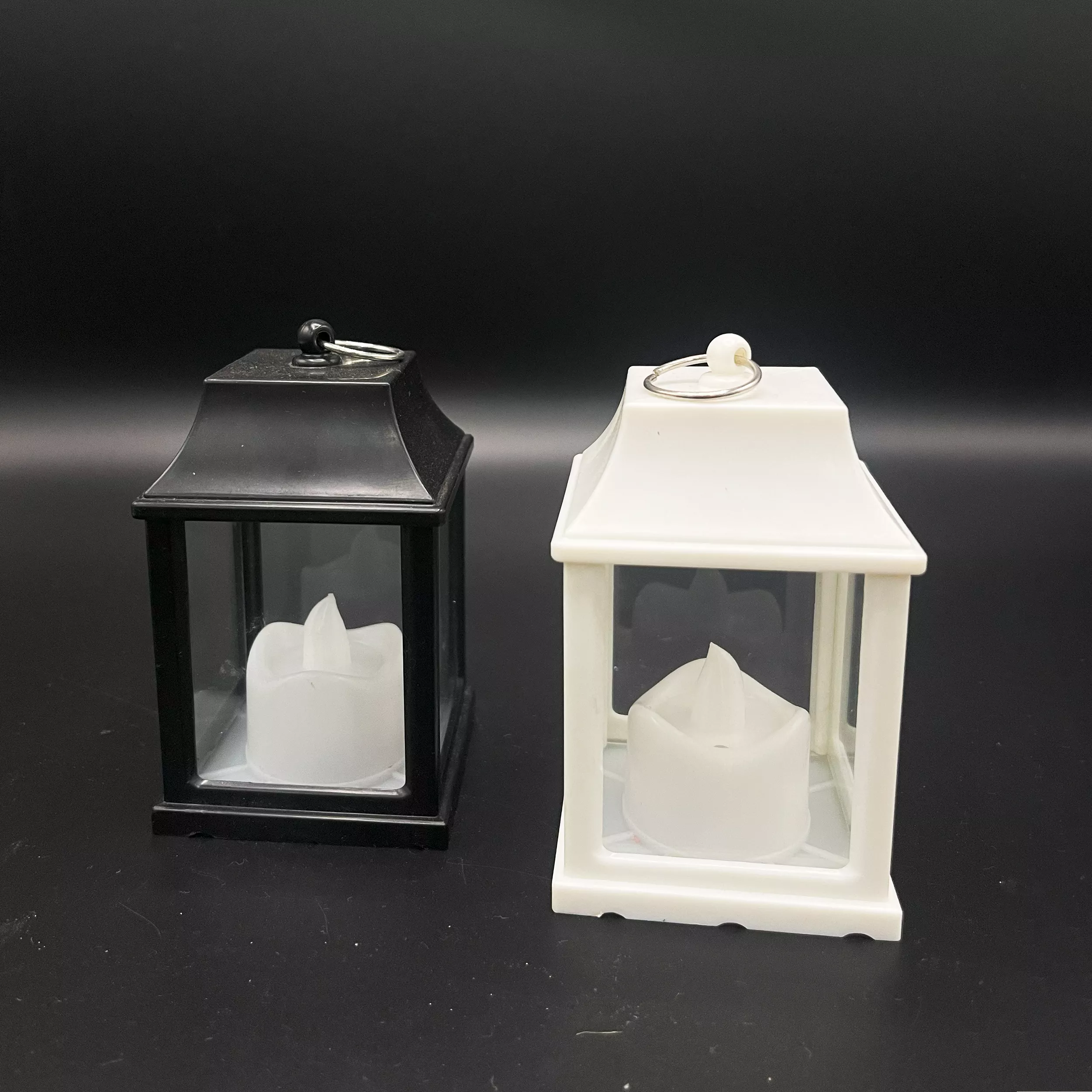 Two simple Lanterns shaped LED candle lights one black and one white.