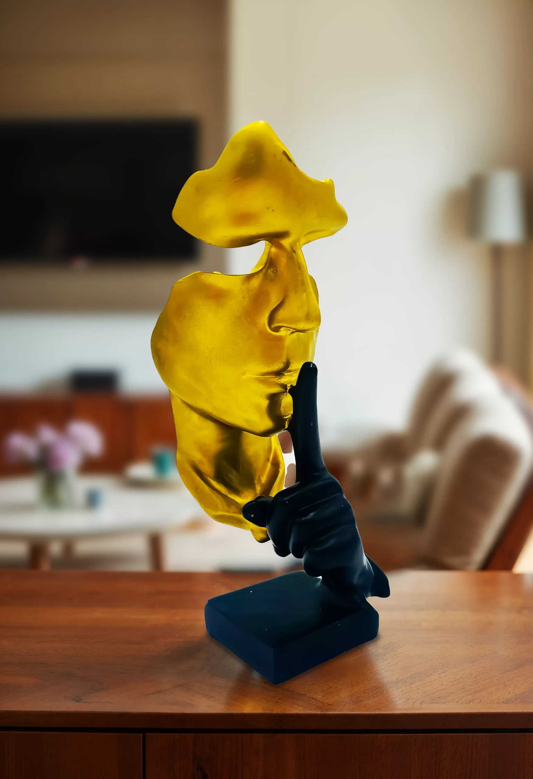 Gold Thinker face scaled statue on a wooden table in a living room setting.