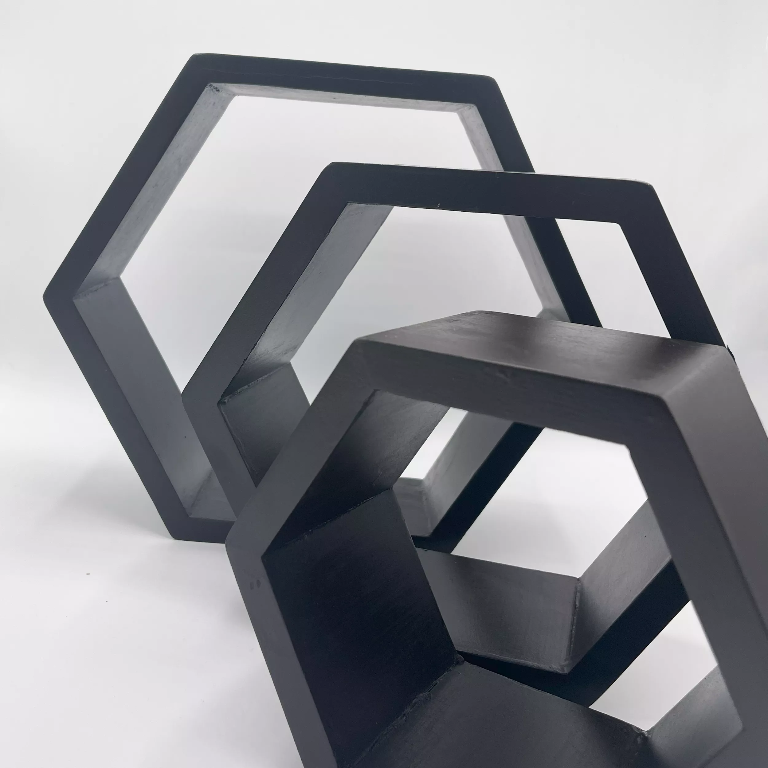 Close-up of three Black Hexagonal wood shelves, stacked diagonally.