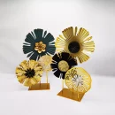Two sets of modern metallic flower tabletop decor, in gold, black, and dark green, on gold stands, against a light background.